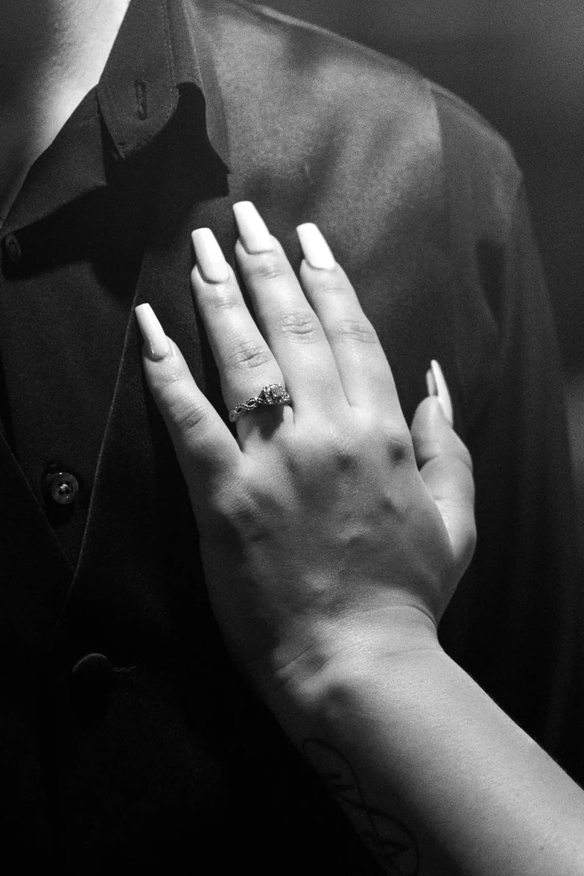An open hand resting on the chest, in soft monochrome light